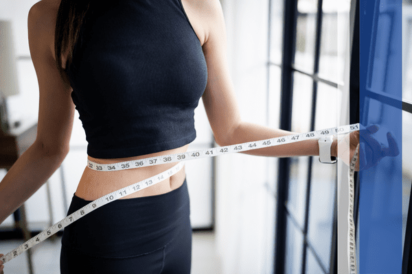 Woman measuring waist with tape measure.