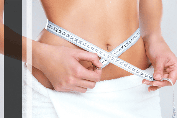 Woman measuring waist with tape.